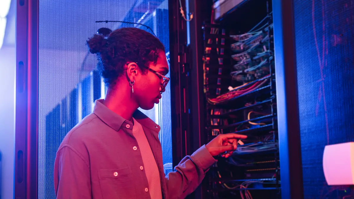 engineer inspecting cables at a lit server rack